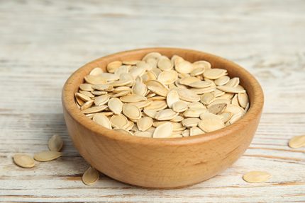 Bowl,Of,Raw,Pumpkin,Seeds,On,White,Wooden,Table